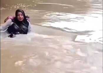 Bidan Dona Lubis saat menyeberangi sungai.[foto : ist]