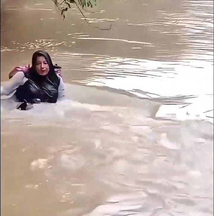 Bidan Dona Lubis saat menyeberangi sungai.[foto : ist]