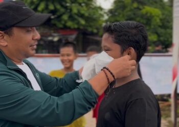 Ketua DPW PKB Sumbar, Firdaus saat memasangkan masker kepada warga.[foto: ist]