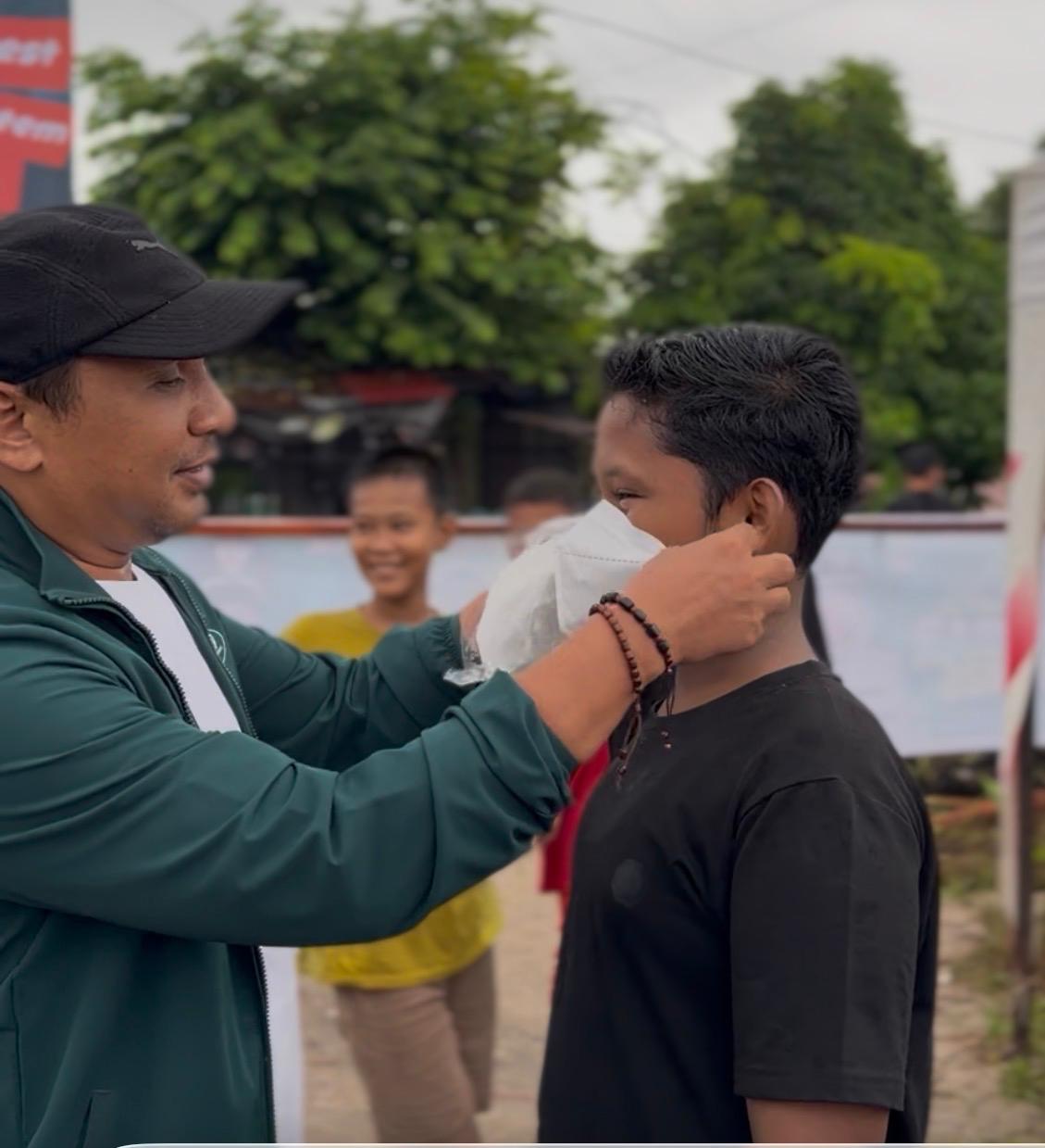 Ketua DPW PKB Sumbar, Firdaus saat memasangkan masker kepada warga.[foto: ist]